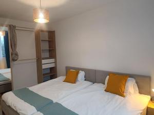 1 dormitorio con 1 cama grande con almohadas amarillas en Appartement aux Portes de Paris, métro 12, en Aubervilliers