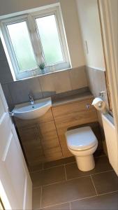 a bathroom with a toilet and a sink and a window at Cute 2 bedroom house Littleover close to amenities hospital in Derby