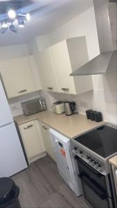a kitchen with white cabinets and a stove top oven at Cute house Littleover close to amenities hospital in Derby