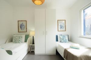 Porto FormosoにあるCasa Da Praiaの白い部屋で、ベッド2台、窓が備わります。