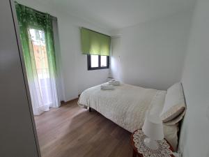 Habitación blanca con cama y ventana en CASA CATALINA en Priego de Córdoba