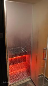 een glazen douche met rode verlichting in de badkamer bij Nell'aqua in Seneffe