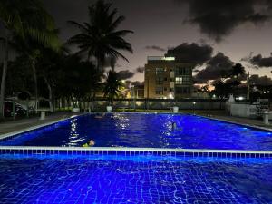 a large pool with blue lights in a city at night at Charmante Maison dans residence Privé Tropicaliente prés de Porto de Galinhas in Porto De Galinhas