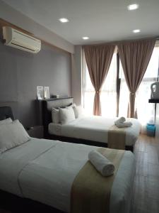 a hotel room with two beds and a window at Sunset Villa Inn in Pantai Cenang