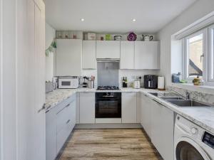 a white kitchen with white cabinets and appliances at Pass the Keys Modern Quiet House Airport Links Pass the Keys in Cheadle