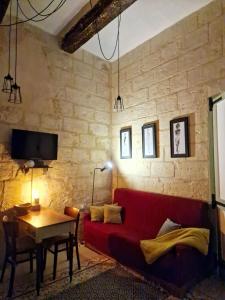 a living room with a red couch and a table at Myrtle Suite - Valletta ground floor apartment in Valletta