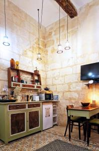 a kitchen with a table and a tv in it at Myrtle Suite - Valletta ground floor apartment in Valletta
