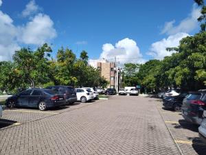 Um monte de carros estacionados num parque de estacionamento. em Flat no loa Resort & Residence na Barra de São Miguel
