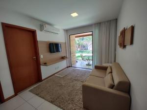 een woonkamer met een bank en een glazen schuifdeur bij Flat no loa Resort & Residence in Barra de São Miguel