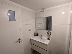La salle de bains blanche est pourvue d'un lavabo et d'un miroir. dans l'établissement Private room in shared Apartment, à Jérusalem