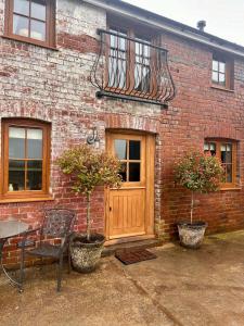 a brick building with a wooden door and a balcony at Historic cottage with oak beams & period charm in Llangadog