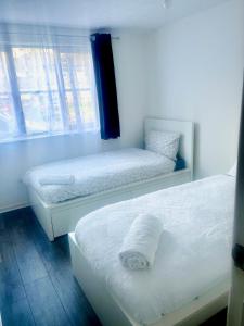 two beds sitting in a room with a window at Comfortable and Cosy London Stay in London