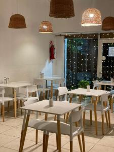 un restaurante con mesas blancas, sillas y luces en Hotel Lobo de Mar - Las Heras en Mar del Plata