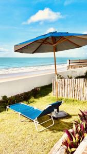 einen Strandkorb und einen Sonnenschirm am Strand in der Unterkunft Casa Prema - Experiência vegana e terapêutica à beira-mar in Maceió