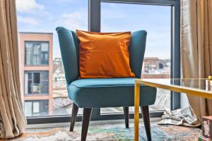 an orange pillow sitting on a chair in front of a window at Vibrant Bliss - Vibrant 2BED 2BATH Birmingham in Birmingham