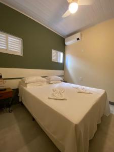 - une chambre avec un grand lit et des draps blancs dans l'établissement Pousada Aracê, à Pedra Azul