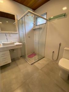 a bathroom with a shower with a sink and a toilet at Pousada Aracê in Pedra Azul