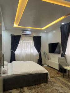 um quarto com uma cama, uma televisão e uma cadeira em Cozy Studio in Asokoro+fast WiFi em Aso