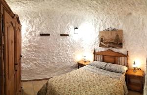 CASA CUEVA EL OLIVO في Pegalajar: غرفة نوم بسرير وجدار ابيض