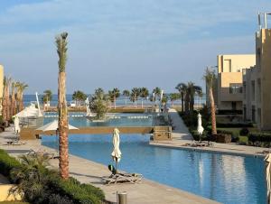 a swimming pool with chairs and umbrellas in a resort at Fabulous Sea view 1 BR & private Garden to the pool at Mangroovy in Hurghada