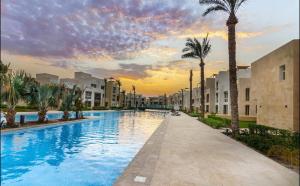 a swimming pool with palm trees and buildings at Fabulous Sea view 1 BR & private Garden to the pool at Mangroovy in Hurghada