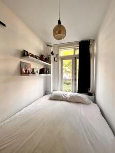 a bedroom with a large white bed with a window at Lovely, light and calm 1-bedroom apartment in Amsterdam