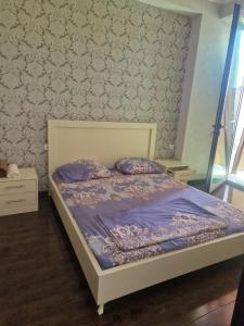 a bedroom with a bed with purple comforter at vekuas apartments in Tbilisi City