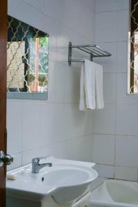 uma casa de banho branca com um lavatório e uma janela em Naalya Motel em Kampala
