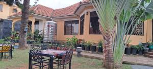 uma mesa e cadeiras em frente a uma casa em Naalya Motel em Kampala
