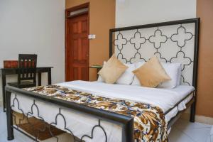 um quarto com uma cama e uma cabeceira em preto e branco em Naalya Motel em Kampala