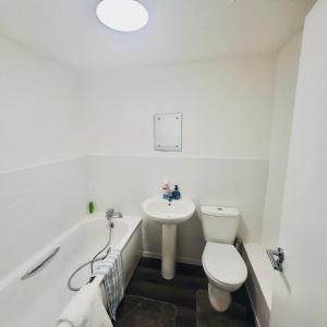 Baño blanco con aseo y lavamanos en Comfortable and Cosy London Stay, en Londres