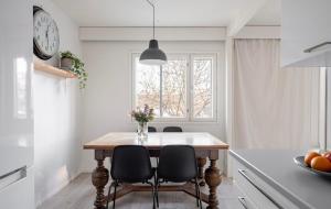 cocina con mesa con sillas y reloj en Bright and spacious condo near subway with FREE parking, en Espoo