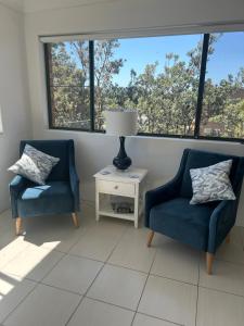 two chairs and a lamp in a room with windows at Beautiful and Bright Penthouse in Hawks Nest