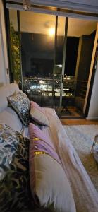 uma cama com almofadas num quarto com uma grande janela em Apartament central y acogedor AIRE ACONDICIONADO Y WIFI em Rancagua
