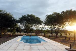 a swimming pool in a park with trees at La Pausa. Casa de campo in Deán Funes