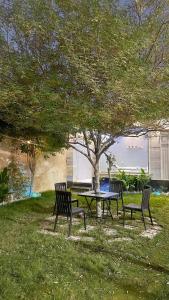 a picnic table and two chairs under a tree at شالية ديور الفندقي in Al Wudayy