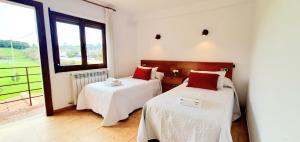 two beds in a room with a large window at Sidreria La Casa Abajo in La Franca