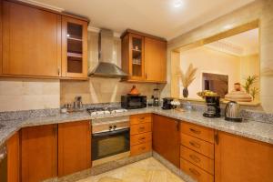 a kitchen with wooden cabinets and a stove top oven at Appartement Haut Standing Gueliz Plaza avec Vue in Marrakesh