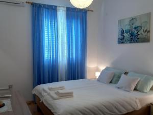 a bedroom with a large bed with blue curtains at Apartments by the sea Sali, Dugi otok - 8117 in Sali