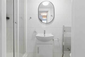 a white bathroom with a sink and a mirror at Hyde Park/Paddington Flat in London
