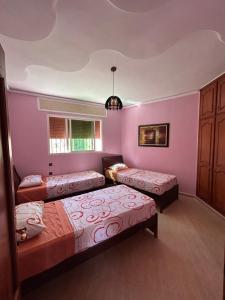 2 Betten in einem Zimmer mit rosa Wänden in der Unterkunft Villa luxueuse et familiale in Tétouan