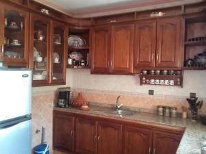 una cocina con armarios de madera y fregadero en Villa luxueuse et familiale, en Tetuán