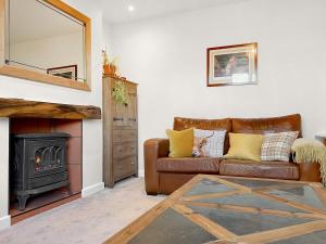 a living room with a leather couch and a fireplace at Middle Farm Cottage in Avebury