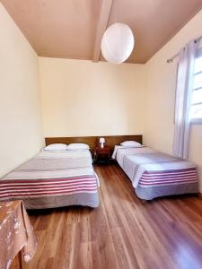 two beds in a room with wooden floors and a window at Inka Roots Hostel in Arequipa