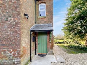 a brick building with a green door and a window at Middle Farm Cottage in Avebury