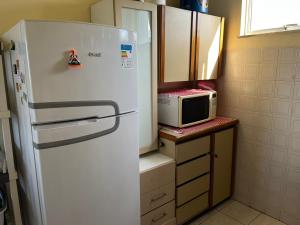 a kitchen with a white refrigerator and a microwave at Apartamento Aluguel Morro Branco. in Beberibe