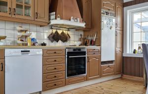 una cocina con armarios de madera y electrodomésticos blancos en Beautiful Home In Kolvereid With Kitchen en Kolvereid