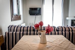 a vase with red flowers on a table in a living room at Nymfes in Tsagarada