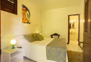 1 dormitorio con 1 cama y 1 mesa con lámpara en Regina Apartments, en Morro de São Paulo