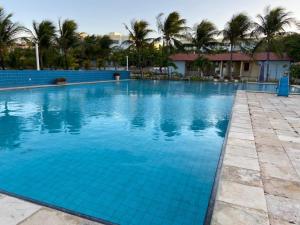 a large blue swimming pool with palm trees in the background at Apartamento Aluguel Morro Branco. in Beberibe